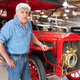 Jay Leno standing with the 1907 White Steam Car that caught fire.